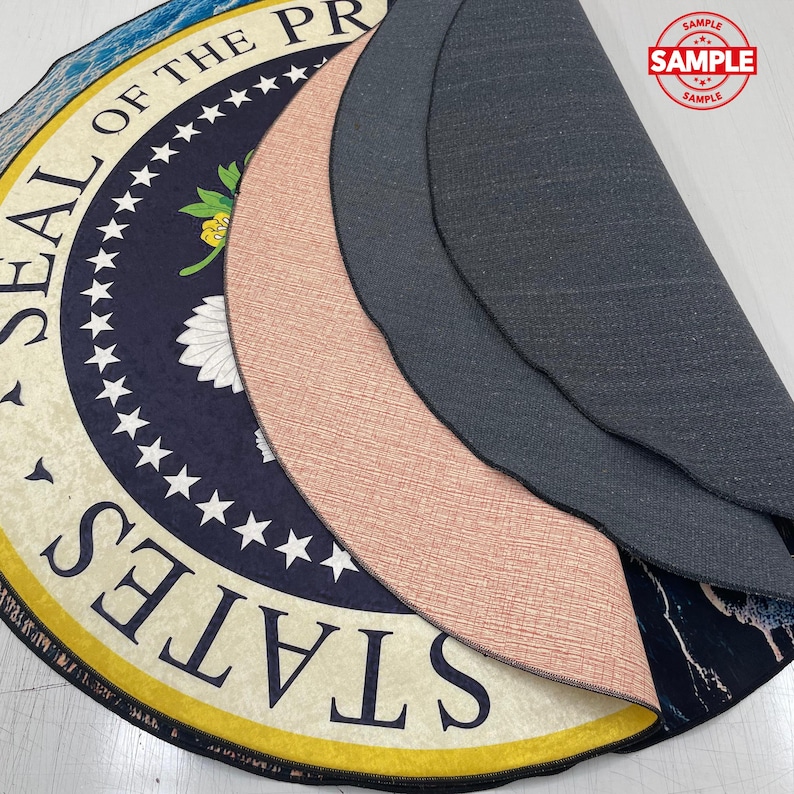 May include: Circular rug displaying the Presidential Seal in navy blue and cream. The rug has a yellow border and a black backing. The word "SAMPLE" is stamped on the rug.