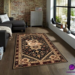 May include: A rectangular area rug with a black background and a detailed floral pattern in beige, brown, and gold. The rug features a central image of a deer. The rug is placed on a wooden floor in a living room setting.