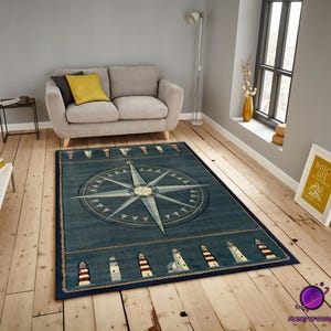 May include: A rectangular blue nautical rug with a compass rose design. The rug has a border of lighthouses and rope detailing. It is placed on a wooden floor in a living room. The rug measures approximately 200cm x 300cm.