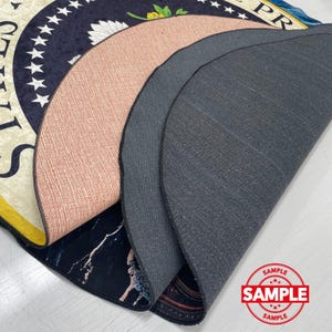 May include: A layered view of several circular rugs, showcasing their varied designs and textures. One rug displays a navy blue pattern with white stars and text, while another has a pinkish-brown textured surface. The bottom rug features a black and white marble design.