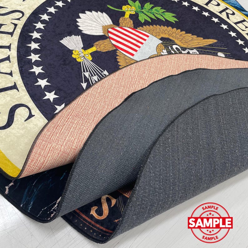 May include: A layered rug with the Presidential Seal design, featuring a navy blue background with white stars and a central eagle emblem. The rug's edges reveal different textures and colours, including a peach and grey layer. A "SAMPLE" stamp is visible.