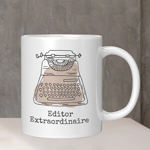 May include: White ceramic mug with a black and brown illustration of a vintage typewriter. The text "Editor Extraordinaire" is printed below the typewriter.