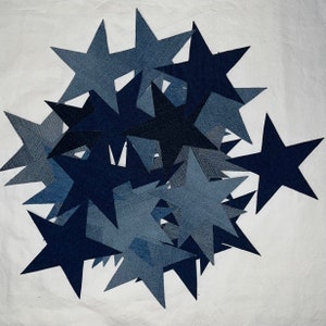 May include: A pile of blue denim fabric stars, some are a darker blue than others. The stars are all the same size and shape.