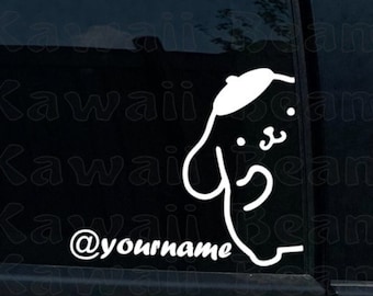 May include: A white vinyl decal applied to a dark car window, featuring a cartoon dog character wearing a beret and the custom text @yourname in a stylised script font. The design is composed of clean white lines against the dark glass.
