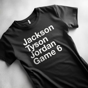 Puede incluir: Camiseta negra de cuello redondo con texto blanco "Jackson Tyson Jordan Game 6". La camiseta está hecha de un material suave y es adecuada para ropa casual.