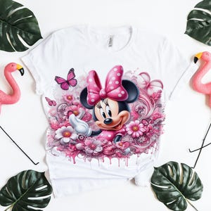 May include: White t-shirt with a pink and white cartoon image of Minnie Mouse surrounded by pink flowers.