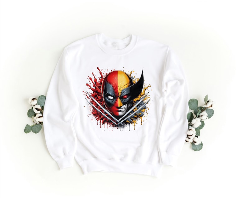 May include: White sweatshirt with a graphic print of Deadpool and Wolverine's faces, with their claws crossed, in a red, yellow, and black color scheme.