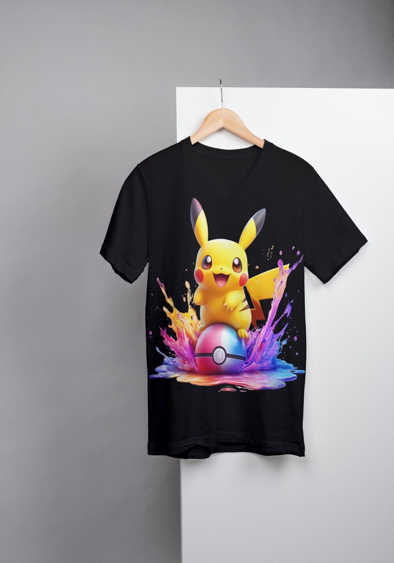 May include: Black V-neck t-shirt with a colorful graphic of Pikachu sitting on a Pokeball surrounded by colorful paint splatters.