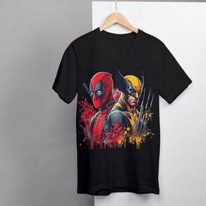 May include: Black V-neck t-shirt with a graphic print of Deadpool and Wolverine in a splash of red and yellow paint.