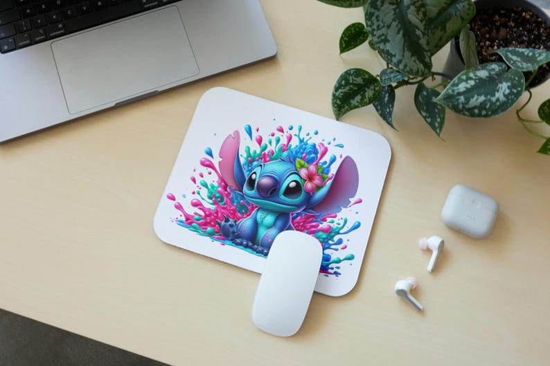 May include: A blue and white cartoon character with large ears and a flower in its hair, surrounded by pink, blue, and green paint splatters. The character is on a white mouse pad.