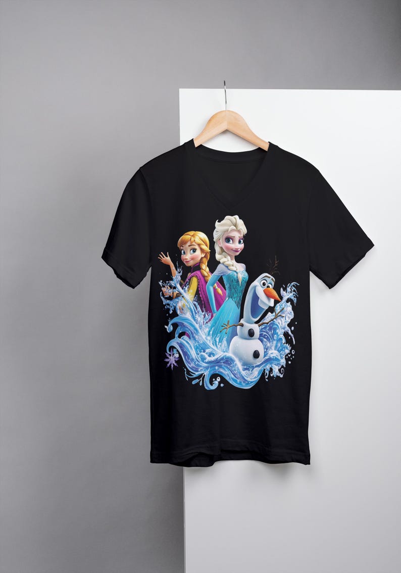 Pu&ograve; includere: Maglietta nera a collo a V con una stampa grafica colorata di Elsa e Anna di Frozen, in piedi in un'onda d'acqua con Olaf il pupazzo di neve.