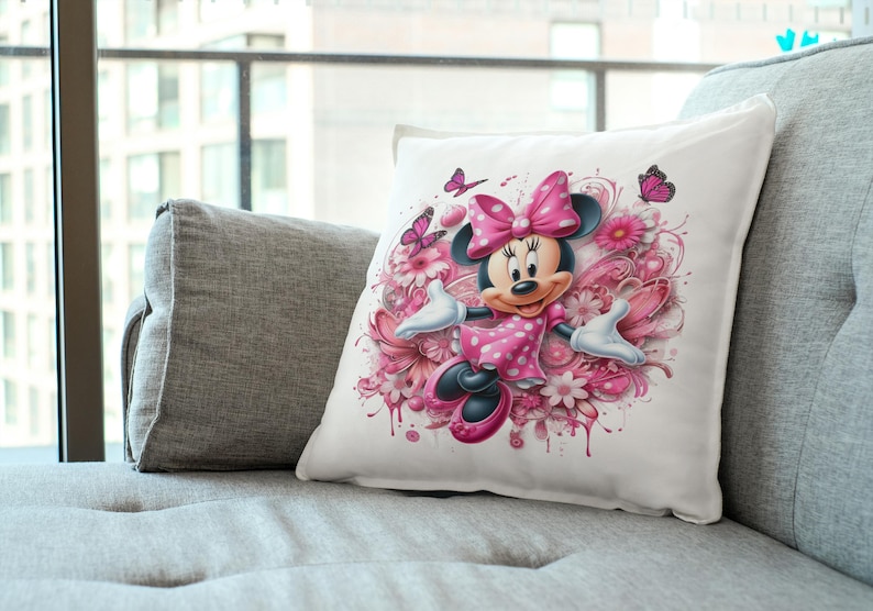 May include: A white pillow with a pink and white floral design featuring Minnie Mouse in a pink polka dot dress.  She is surrounded by pink flowers and butterflies.