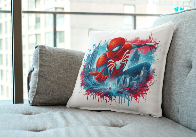 May include: A white pillow with a colorful graphic of Spider-Man swinging through a city skyline. The graphic features a red and blue Spider-Man suit with a white spider logo. The background is a blue and red watercolor effect.