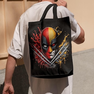 May include: A black tote bag with a graphic of Deadpool and Wolverine's faces, with red and yellow paint splatters and their signature weapons.