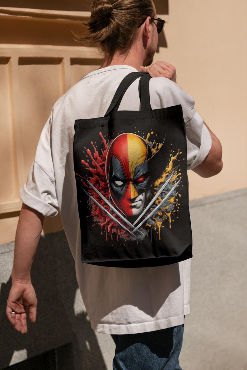 May include: A black tote bag with a graphic of Deadpool and Wolverine's faces, with red and yellow paint splatters and their signature weapons.