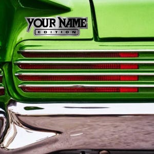 Puede incluir: Un coche verde con un parachoques cromado y una calcoman&iacute;a plateada que dice "YOUR NAME EDITION".