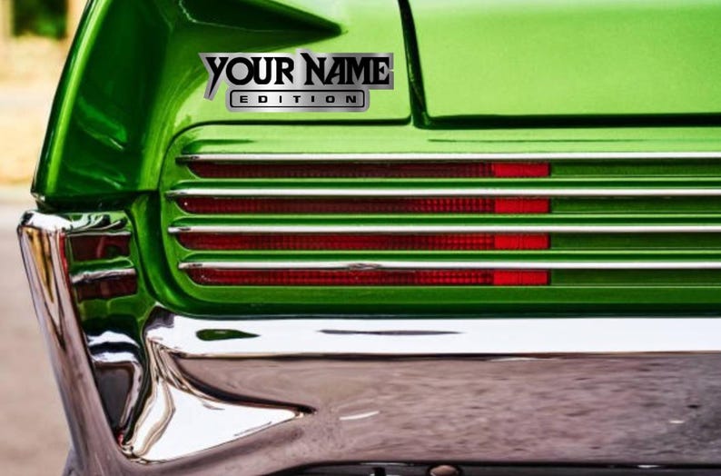 Puede incluir: Un coche verde con un parachoques cromado y una calcoman&iacute;a plateada que dice "YOUR NAME EDITION".