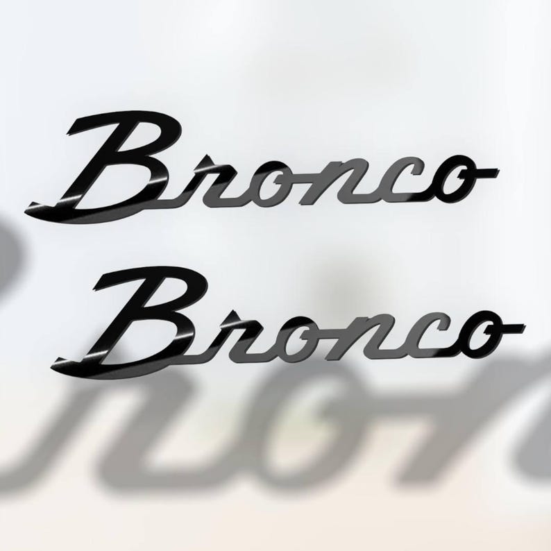 May include: Two black "Bronco" wordmark emblems, one above the other, with a glossy finish. The wordmark has a stylized script font. The emblems are set against a white background, with a shadow effect.