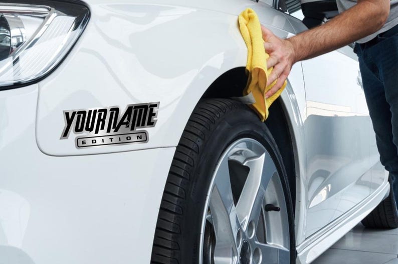Puede incluir: Un coche blanco con una calcoman&iacute;a negra y plateada que dice "YOUR NAME EDITION".