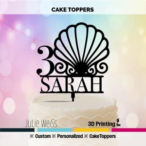Op de afbeelding: Zwarte taarttopper met het nummer 30 en de naam SARAH, bekroond met een schelpmotief. De woorden "CAKE TOPPERS" staan bovenaan. De taarttopper staat op een witte taart.