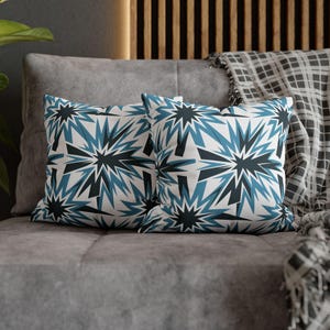 May include: Two decorative throw pillows with a geometric pattern of blue and black stars on a white background.