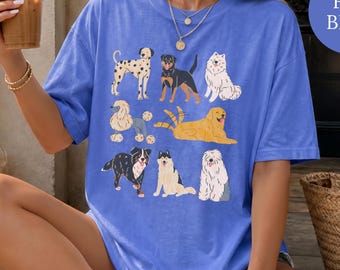 Könnte beinhalten: Ein kurzärmeliges T-Shirt in Kornblumenblau mit einem Grafikdruck von neun verschiedenen Hunderassen, die in einem Raster angeordnet sind. Zu den Hunden gehören ein Dalmatiner, Rottweiler, Samojede, Pudel, Golden Retriever, Australian Shepherd, Husky und Bobtail.