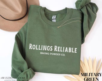 Könnte beinhalten: Ein militärgrünes Langarm-Sweatshirt mit Rundhalsausschnitt und dem weißen Schriftzug Rollings Reliable Baking Powder Co. auf der Brust. Das Kleidungsstück hat einen gerippten Kragen, Bündchen und Saum sowie ein sichtbares Markenetikett am Halsausschnitt.