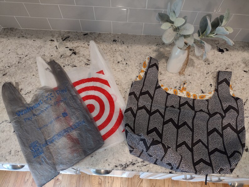 May include: Three reusable shopping bags. Two are plastic bags with the logos "Walmart Pay" and "Target" printed on them. The third bag is a black and white fabric bag with a chevron pattern.