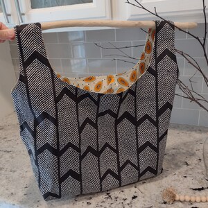May include: A black and white chevron patterned tote bag with a papaya print lining. The bag has a wooden handle.