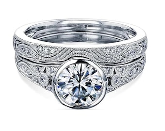May include: A silver engagement ring set with a large round center stone and intricate filigree detailing. The band is adorned with smaller diamonds.