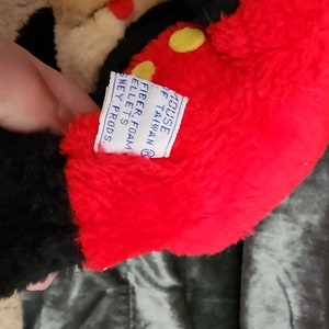 May include: Black and red plush Mickey Mouse toy with a yellow button on the chest. The tag reads "House of Mouse, Taiwan, Fiber Foam Pellet's, Disney Prods."