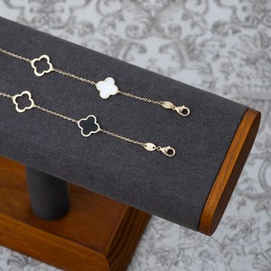 Puede incluir: Dos pulseras de cadena dorada con dijes en forma de tr&eacute;bol. Una pulsera tiene tr&eacute;boles de esmalte negro y la otra tiene tr&eacute;boles de esmalte blanco.