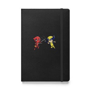 Puede incluir: Cuaderno negro con una ilustración de dibujos animados de Deadpool y Wolverine. El cuaderno tiene un cierre elástico negro.