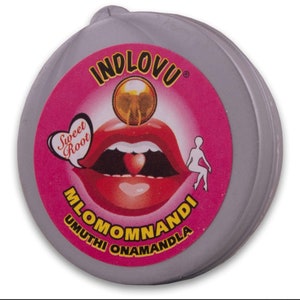 May include: A round, pink and grey container with a red, open mouth and a heart-shaped sweet inside. The container has the text "INDLOVU" in black letters, "Sweet Root" in a heart shape, "MLOMOMNANDI" in black letters, and "UMUTHI ONAMANDLA" in black letters.
