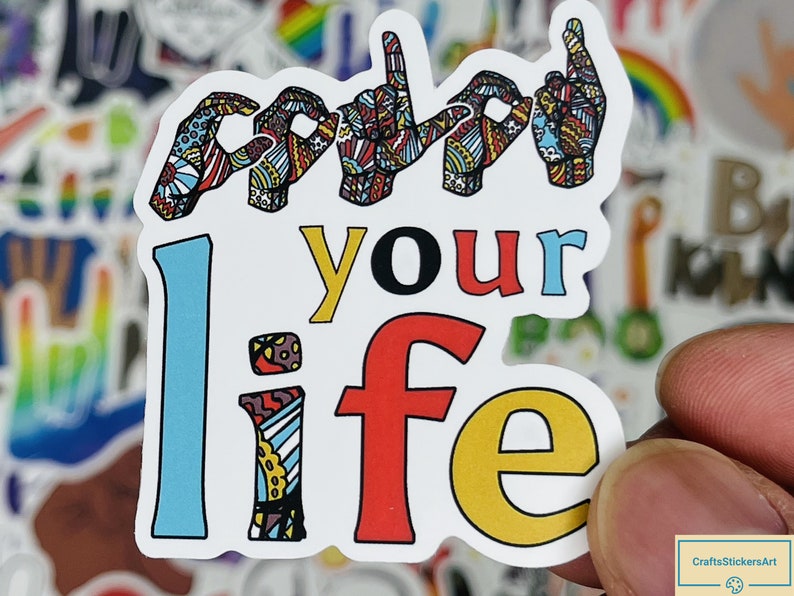 May include: White sticker with the text "sign your life" in colourful letters. The word "sign" is depicted with five colourful hands in the British Sign Language sign for "sign".