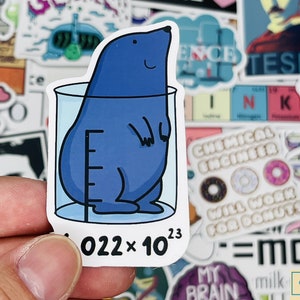 May include: A blue cartoon mole is inside a beaker with a graduated scale. The beaker is on a white background with the text "022 x 10^23" below it.
