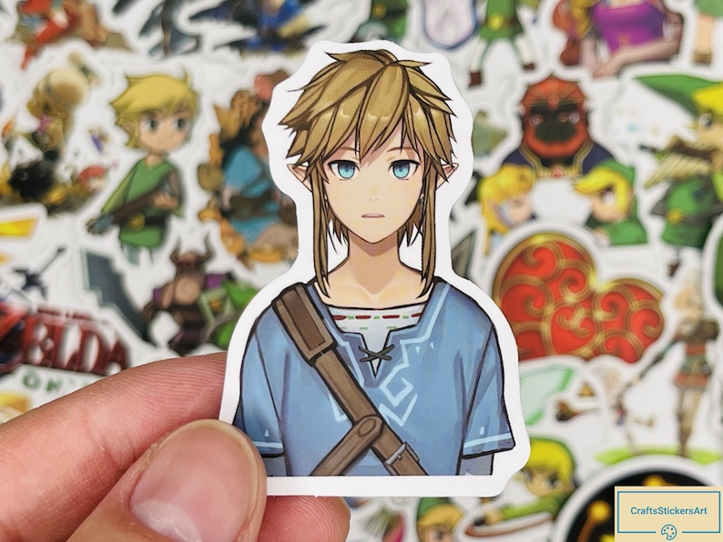 May include: A sticker featuring a cartoon illustration of Link from the Legend of Zelda video game series. Link is wearing a blue tunic with a brown strap and has blonde hair and blue eyes.