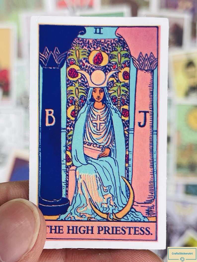 May include: A tarot card sticker with a colorful illustration of the High Priestess. The card is pink, blue, and yellow with a woman in a white robe sitting on a throne. The card has the Roman numeral II and the text "THE HIGH PRIESTESS."