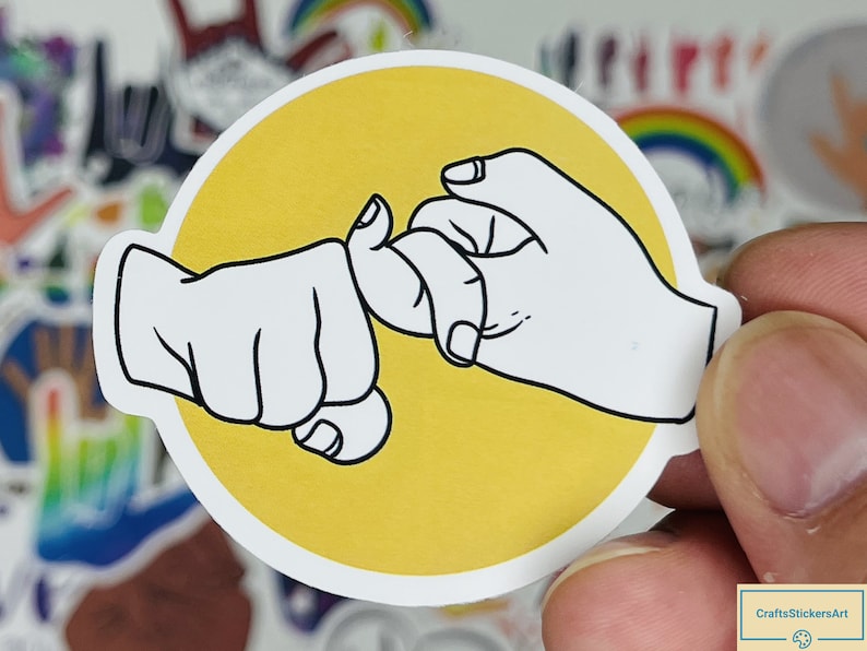 May include: A yellow circle sticker with a black outline features two hands making a pinky promise. The hands are white with black outlines.