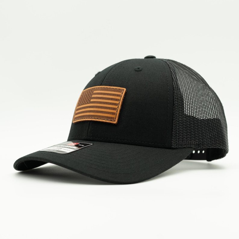 Add a patriotic touch to your look with our black/black Richardson 115 or 112 hat. Featuring a hand-sewn American flag leather patch, adjustable Snapback, and made in Colorado, USA for quality you can trust! Trucker cap with mesh back.