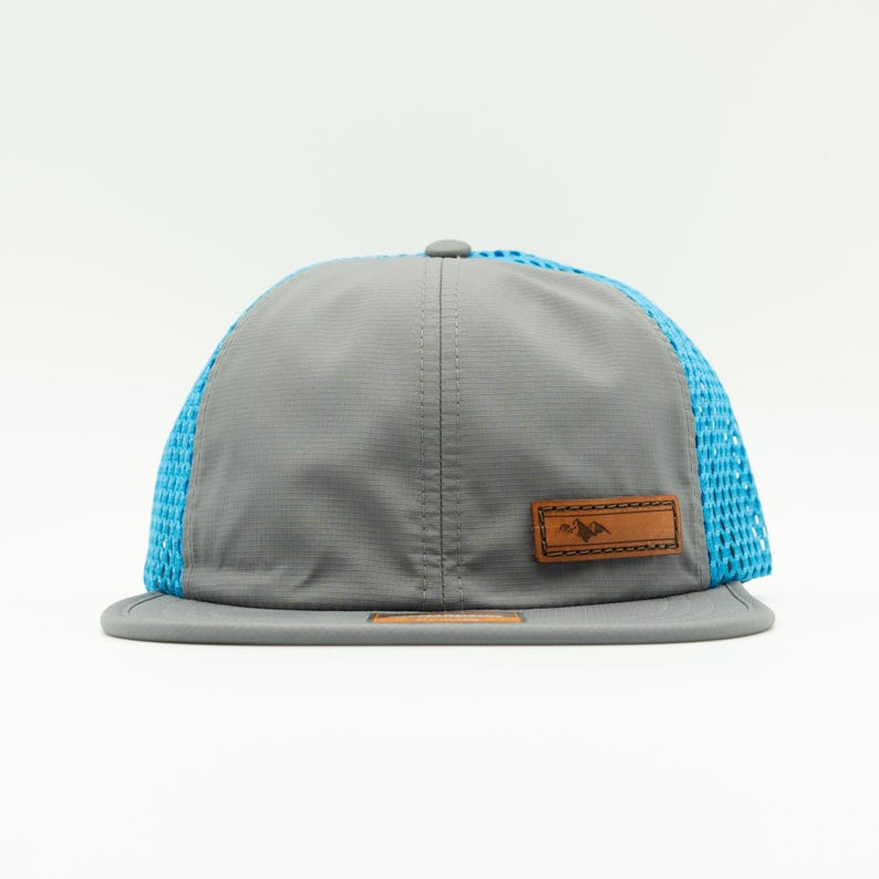 Front angle of gray and Cyan Richardson 935 water resistant performance hat with sewn leather mountain patch and flat style bill, lightweight packable outdoors hat