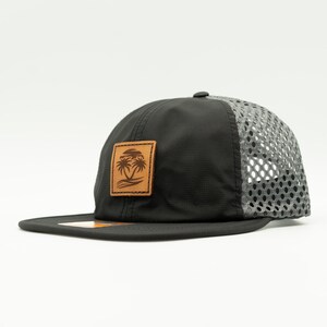 May include: Black and gray mesh baseball cap with a brown leather patch featuring a palm tree design.