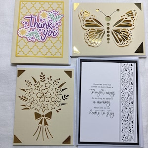 May include: Four handmade greeting cards. One card has a floral design with the words "Thank You". Another features a butterfly cutout. A third card has a bouquet cutout, and the last card has a poem that reads "those we love can never be more than a thought away".