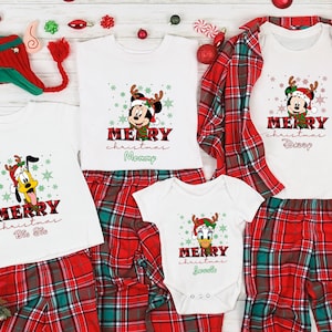 Op de afbeelding: Een bijpassende kerstpyjamaset voor een gezin, bestaande uit rode en groene geruite broeken en witte shirts met een Mickey Mouse en Pluto ontwerp. De shirts hebben de tekst "Merry Christmas" en de namen "Mommy", "Daddy", "Big Sis" en "Little Sis".