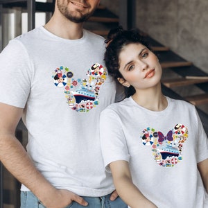 Pu&ograve; includere: T-shirt grigie chiare abbinate con un design a forma di testa di Topolino riempito di elementi nautici e dei cartoni animati. Il design include una nave da crociera, Minnie Mouse e altre grafiche a tema vacanza. Le magliette sono a maniche corte.