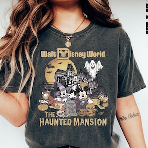 Puede incluir: Una camiseta negra con un gr&aacute;fico de estilo vintage de Mickey Mouse y sus amigos frente a la Mansi&oacute;n Encantada en Walt Disney World. El texto "Walt Disney World" y "The Haunted Mansion" est&aacute; impreso en la camiseta.
