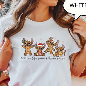 Puede incluir: Camiseta blanca con un dise&ntilde;o festivo de personajes de jengibre. Los personajes est&aacute;n decorados con adornos navide&ntilde;os y est&aacute;n dispuestos en fila. El texto "Stitch's Gingerbread Baking & Co" est&aacute; impreso debajo.