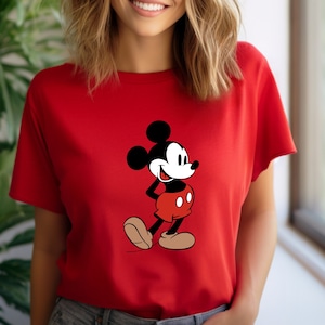 Op de afbeelding: Een rood T-shirt met een zwart-witte afbeelding van Mickey Mouse op de voorkant. Mickey Mouse draagt een rode broek en gele schoenen.