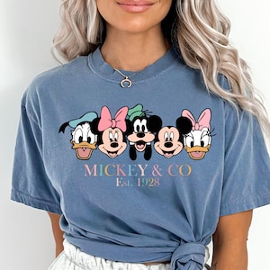 May include: A blue t-shirt with a graphic of Mickey Mouse and friends. The text "MICKEY & CO. Est. 1928" is printed below the graphic.