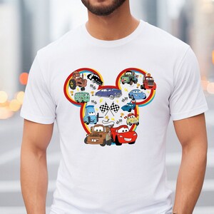 Puede incluir: Camiseta blanca con un dise&ntilde;o de cabeza de Mickey Mouse rojo, amarillo y azul con varios personajes de Cars, incluyendo Rayo McQueen, Mate y Mate remolcador.